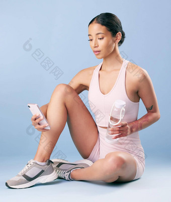 混合比赛健身女人发短信打破锻炼工作室蓝色的背景年轻的拉美裔女运动员发送文本消息采取休息健康健身