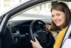 有吸引力的年轻的业务女人肩膀开车车司机微笑相机快乐千禧女人出租车司机坐着车持有操舵轮