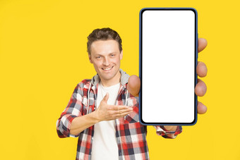 介绍应用程序快乐持有巨大的巨大的智能手机白色屏幕金发碧眼的男人。穿红色的格子衬衫男人。电话显示模拟孤立的黄色的背景移动应用程序广告