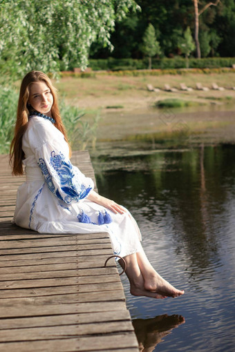 女孩绣花乌克兰衬衫坐在码头反射云水湖海岸天空维希万卡一天自由<strong>爱国</strong>者