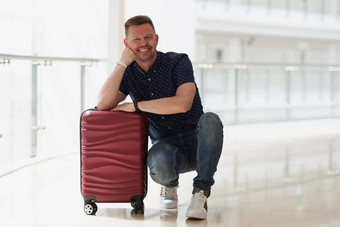快乐微笑男人。摆姿势手提箱规划旅行在国外等待离开机场