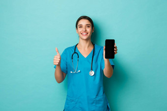 科维德流感大流行医学概念图像微笑美丽的女医生穿实习医生风云显示移动电话屏幕竖起大拇指推荐应用程序蓝色的背景