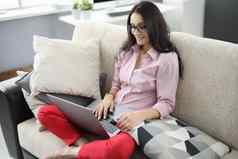 年轻的女人移动PC坐着舒适的沙发首页室内
