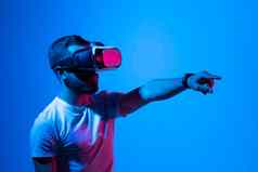 男人。白色t恤穿护目镜元宇宙技术创新虚拟世界概念霓虹灯照明黑暗背景虚拟现实经验未来技术