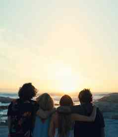 集团朋友拥抱海滩美丽的日落享受夏天假期生活方式