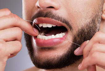 用牙线清洁牙齿男人。用牙线清洁牙齿牙齿工作室背景