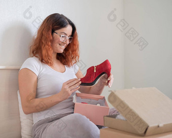 高加索人女人打开命令鞋子坐着床上在线购物概念首页交付