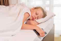 睡眠移动电话美丽的年轻的女孩床上毯子视图说谎概念白色放松快乐平静床上用品睡觉前美在室内舒适的一天谎言