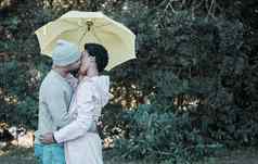 吻共享雨年轻的夫妇接吻站伞