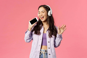 半身照肖像时尚的快乐女人耳机听太棒了跟踪下载卡拉ok应用程序智能手机麦克风唱歌太棒了音乐