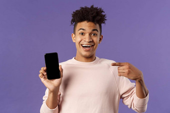 肖像兴奋快乐微笑男人。会说话的应用程序游戏功能指出智能手机显示会说话的移动电话逗乐快乐的表达式
