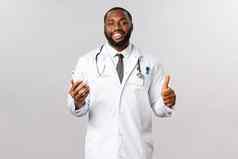 科维德流感大流行在线医学概念英俊的微笑非裔美国人医生显示翘拇指持有智能手机推荐医疗保健医患联系服务应用程序