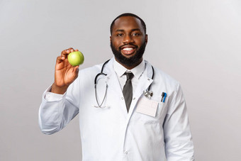 医疗保健医学健康的生活方式概念<strong>好看</strong>的微笑非裔美国人医生建议保持适合吃<strong>水果</strong>由维生素显示苹果病人灰色背景