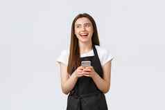 杂货店商店员工小业务咖啡商店概念快乐美丽的女咖啡师女服务员咖啡馆穿黑色的围裙笑左移动电话