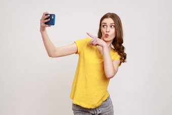 嘿友好的少年女孩黄色的t恤指出手指手机会说话的视频调用移动电话欢迎流媒体在线