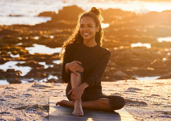 瑜伽实践现在时刻有吸引力的年轻的女人坐着瑜伽席瑜伽会话海滩日落