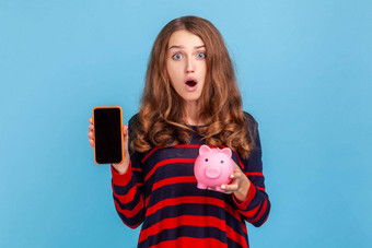 震惊了女人显示智能手机空屏幕摇来摇去促销活动粉红色的小猪银行