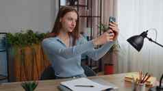 年轻的女人博主采取自拍肖像智能手机社会媒体视频博客工作首页