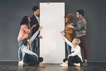 多样化的集团人持有空白白色董事会海报显示广告复制空间团队朋友市场营销榜横幅站坐着促销活动