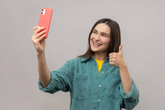 女人显示拇指沟通视频调用流媒体采取自拍智能手机