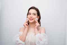 美丽的年轻的微笑女人清洁棉花垫面部治疗美皮肤护理famale脸富有表现力的面部表达式