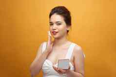 特写镜头美丽的亚洲女人缓冲泡芙镜子应用化妆粉基金会