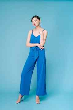 年轻的美丽的女人摆姿势休闲蓝色的时尚服装衣服裤子完整的身体蓝色的背景
