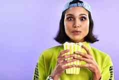 电影使忘记零食工作室拍摄美丽的年轻的女人吃爆米花紫色的背景