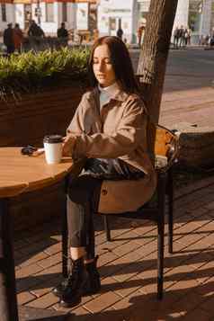 时尚的浅黑肤色的女人女人坐着表格户外咖啡馆咖啡电话秋天走