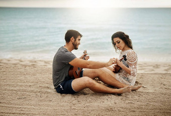 分享爱好分享姓氏年轻的夫妇玩尤克里里琴海滩