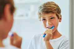 刷牙齿早....快乐的年轻的男孩反射镜子刷牙牙齿浴室首页一天