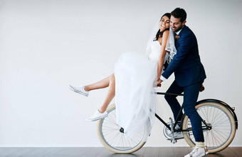 度蜜<strong>月工作</strong>室拍摄新结婚了年轻的夫妇骑自行车灰色的背景