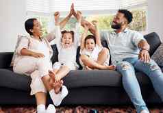 快乐父母兴奋孩子们庆祝沙发看有趣的家庭时间放松首页成键妈妈。父亲高孩子们欢呼体育团队赢得