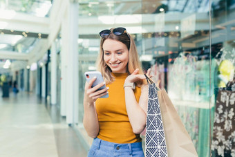 年轻的女人消费者购物中心浏览闲谈，聊天智能手机