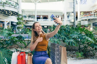 年轻的女人消费者购物中心浏览闲谈，聊天智能手机