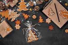 圣诞节姜饼饼干形状圣诞节树玻璃纸包装背景黑暗表格圣诞节礼物概念