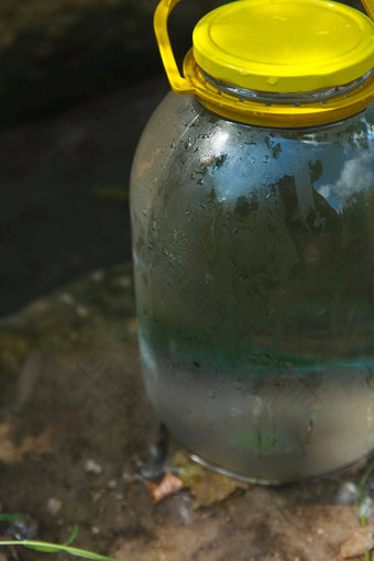 玻璃Jar完整的纯冷春天水站石头自然水春天清晰的喝水概念
