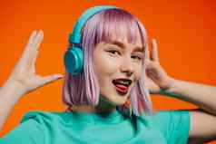 异常女人染色紫罗兰色的头发听音乐耳机唱歌橙色背景独特的赶时髦的人女孩跳舞