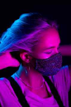 年轻的美丽的时尚女人保护面具莱茵石跳舞晚上俱乐部霓虹灯色彩斑斓的光特写镜头肖像时尚模型