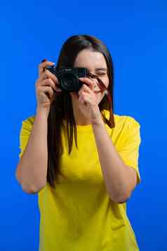 年轻的漂亮的女人需要图片数码单反相机相机蓝色的背景工作室女孩微笑摄影师