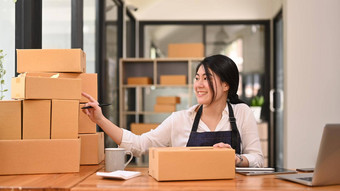 快乐亚洲女企业家准备包裹盒子产品交付做服装的人在线销售电子商务概念