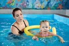 学前教育女孩学习游泳池泡沫面条年轻的教练