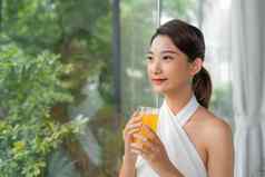 肖像美丽的女人持有玻璃橙色汁坐着首页