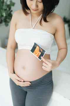 快乐怀孕了女人持有超声波照片肚子