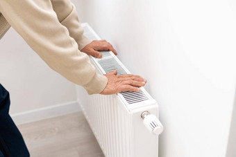 上了年纪的男人。变暖手电加热器淡季中央加热延迟人买额外的加热器房子温暖的增加电账单