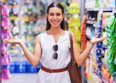 购物零售消费主义女客户站杂货店商店商店超市过道肖像年轻的女人手势产品包装货架上背景
