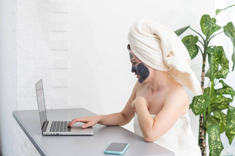 年轻的女人<strong>毛巾</strong>头黑色的面部粘土面具坐着<strong>首页</strong>移动PC电脑住<strong>首页</strong>检疫距离学习在线教育技术现代生活方式