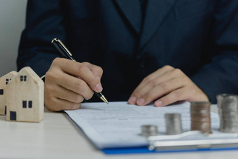 标志房子批准文档真正的房地产评估买出售房子业务概念金融商人持有笔签署文档桌子上