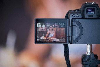 女人影响者数字相机屏幕记录视频博客在线社会媒体视频有创意的年轻的女内容创造者展示互联网网络内容网站播客咖啡馆