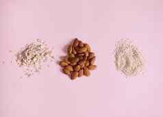 平躺栈有机生素食主义者超级食物杏仁芝麻种子oat-flakes分散粉红色的背景